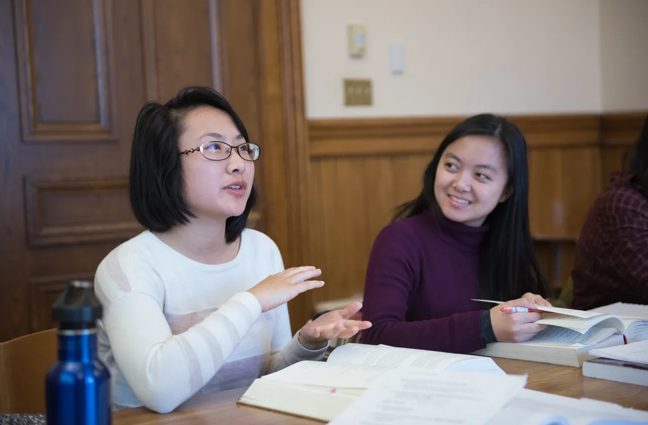 Two students having a discussion in a classroom.