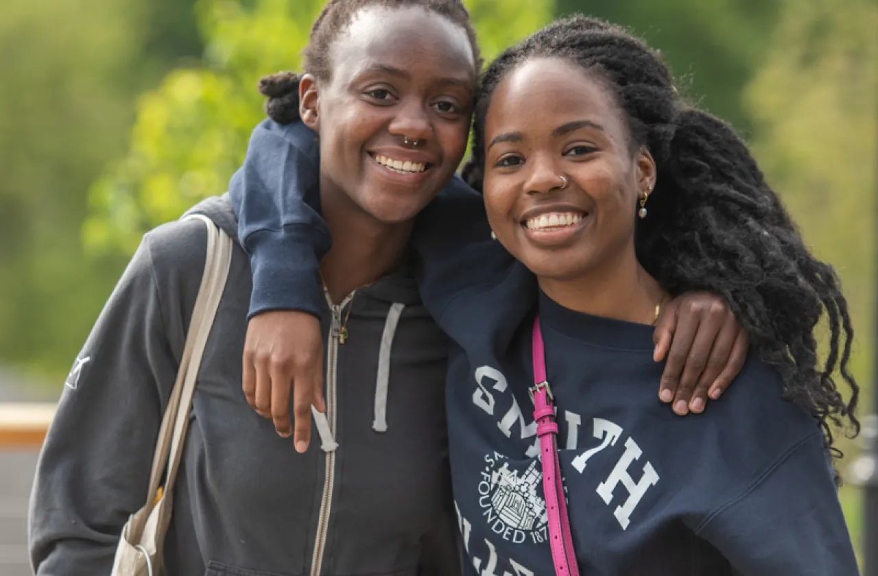 Two alums smiling with their arms around each other.