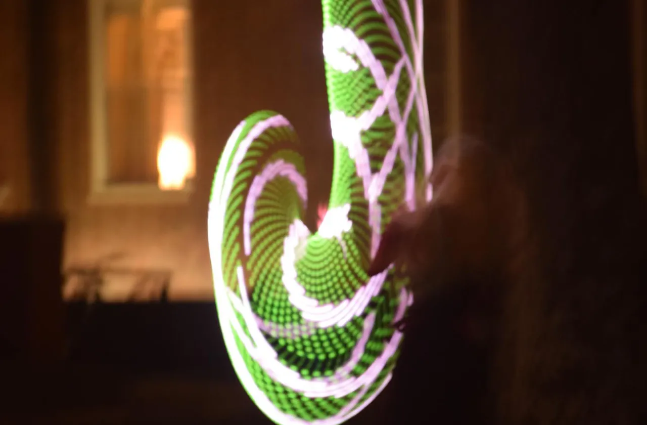 Una Fonte is a blur of green and white color while dancing with LED hula hoops at night