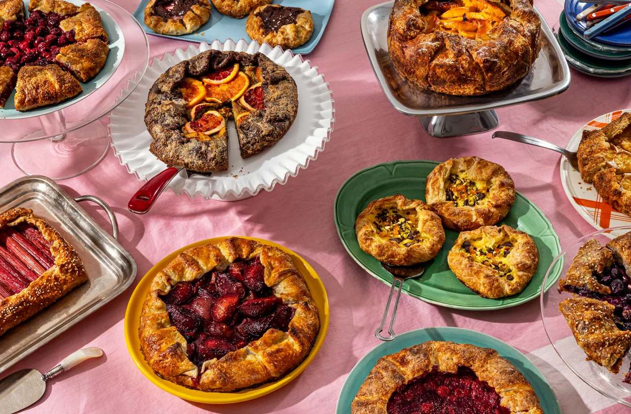 A collection of various galettes on colorful plates, all on a pink tablecloth.