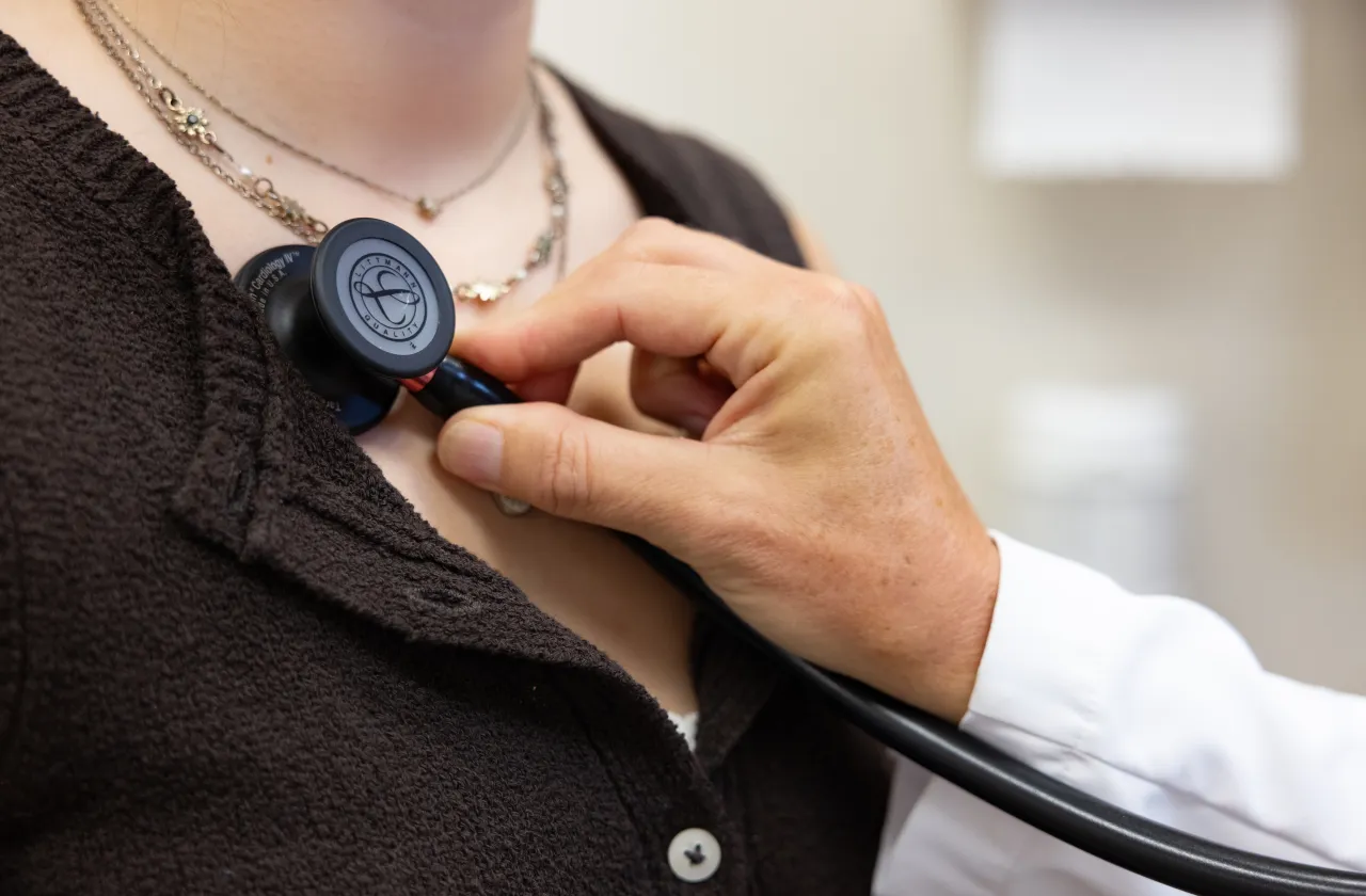 A doctor holding a stethoscope up to a patient's heart