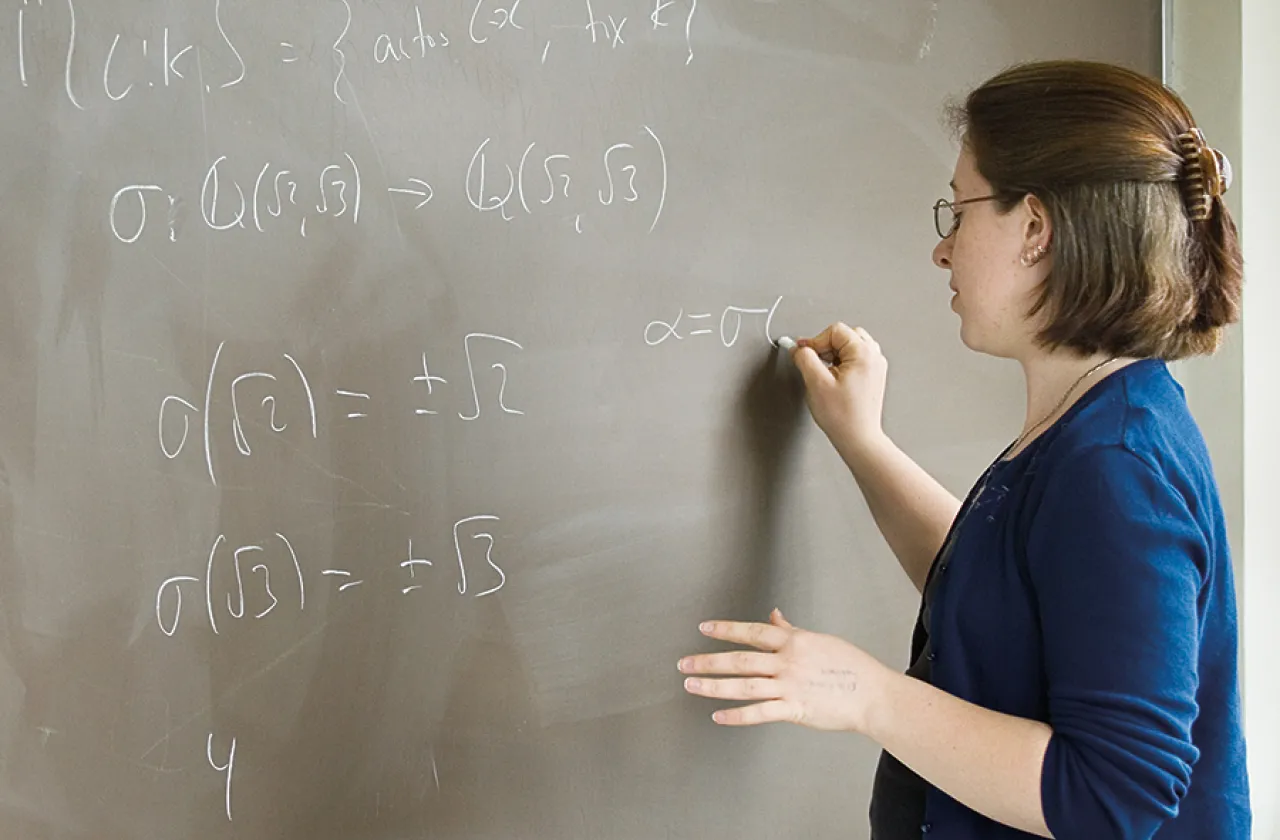 Student working on a math equation at a blackboard