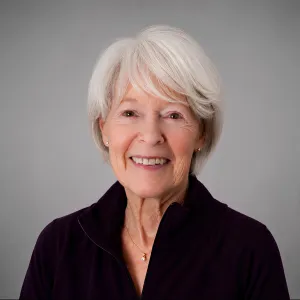 A headshot of Diane Cook in front of a gray background, wearing a black shirt and smiling at the camera.
