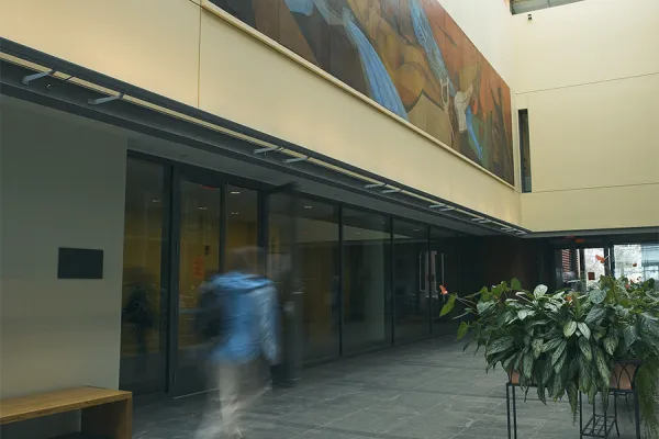 person with backpack walks through the atrium at the museum