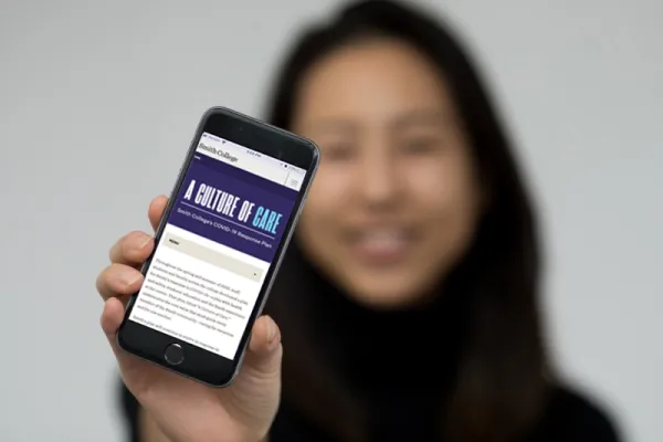 student (blurry) holding a phone (in focus) that shows Smith's Instagram page