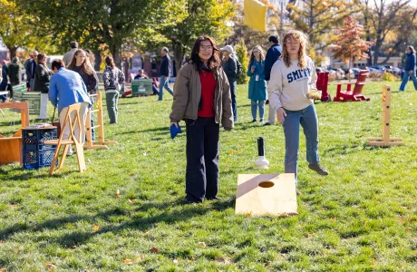 Two people play cornhole during Family Weekend. One is wearing a Smith College sweatshirt.
