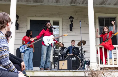 Students play instruments on a porch during Porchfest