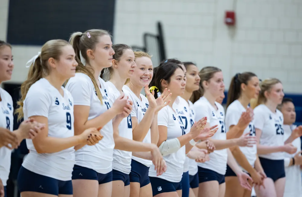 The volleyball team lines up and smiles during a game taking place during Come Home to Smith 2025