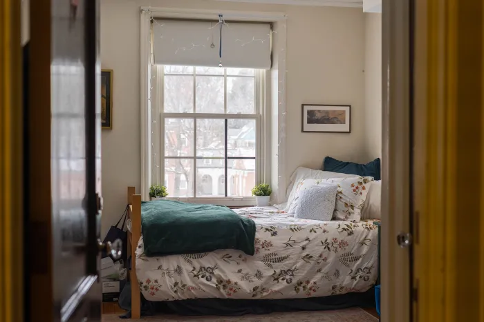 A cozy bed in Emerson House, next to a window.