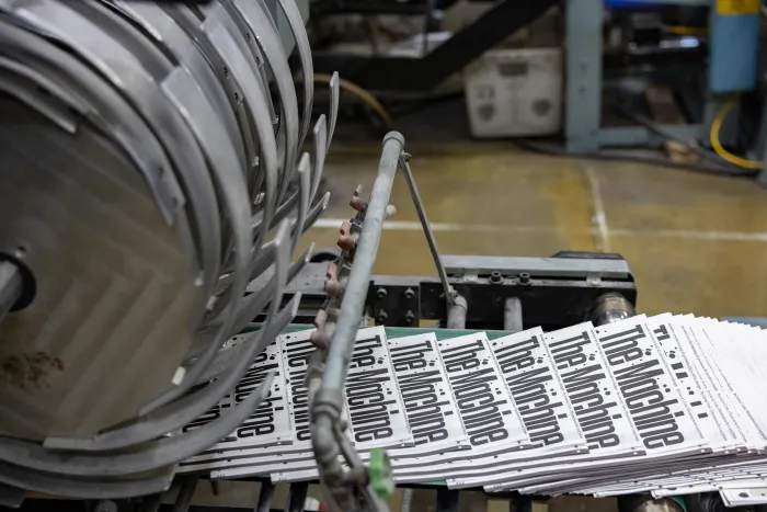 Several printed sheets coming off of the press, layering into a stack