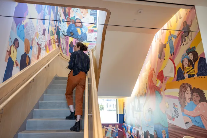 Someone stands on the stairway and admires the new mural in Kathleen McCartney Hall.