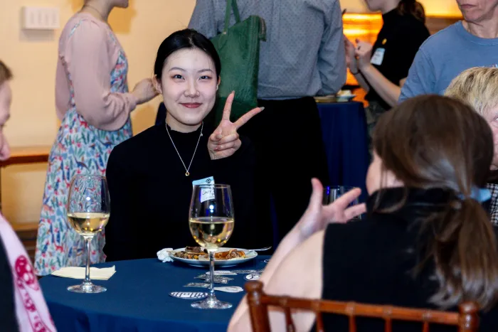 An alum gives the camera a peace sign and a smile.