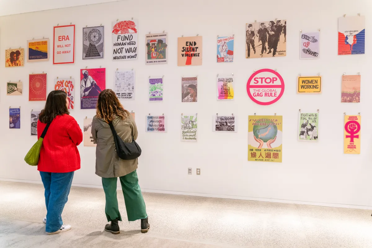 Two attendees talking to each other and admiring political art in a gallery presentation
