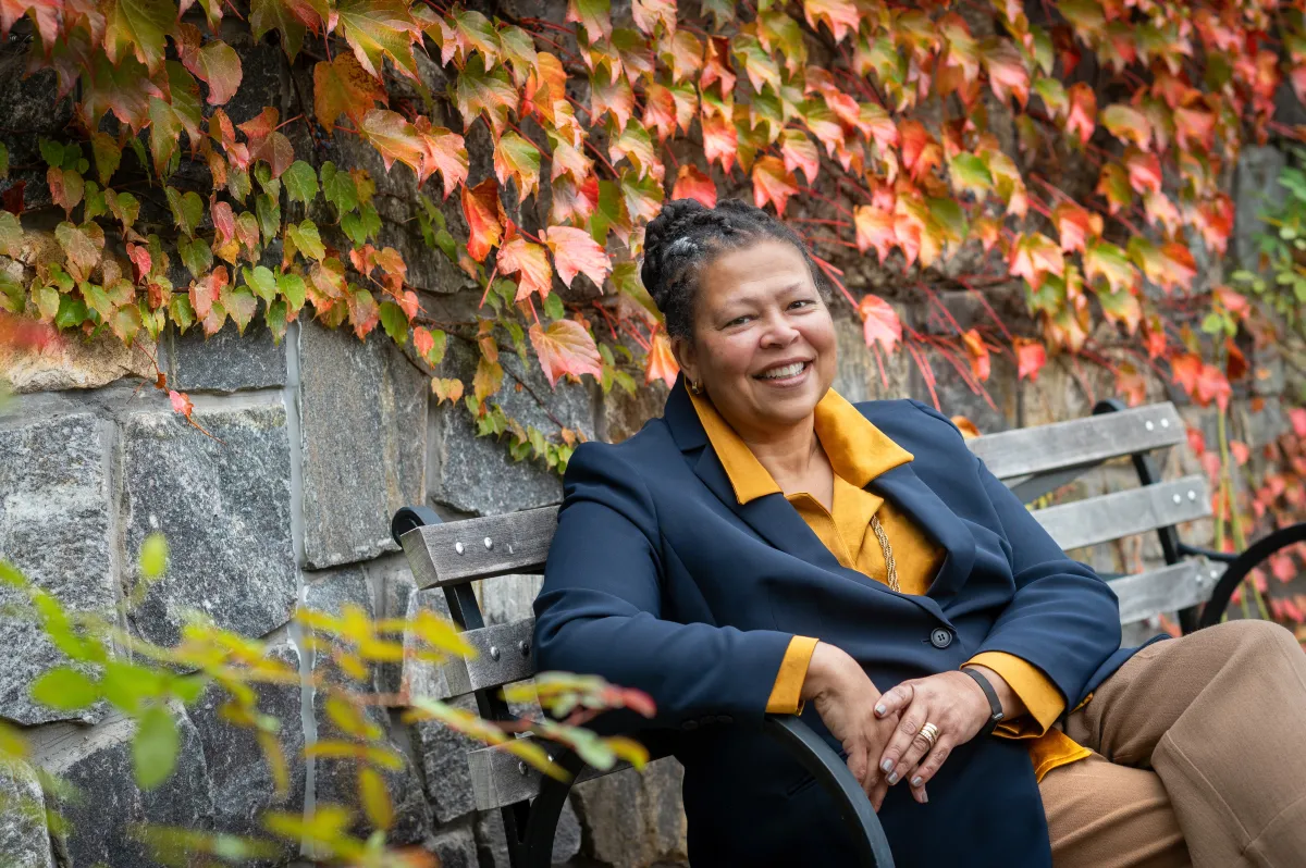 Sarah Willie-LeBreton smiling outdoors and sitting on a bench.