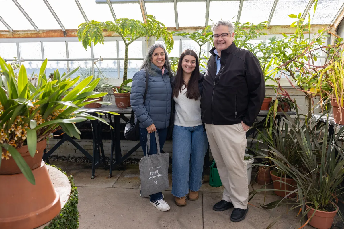 A Smithie poses with her parents in the greenhouse during Family Weekend.