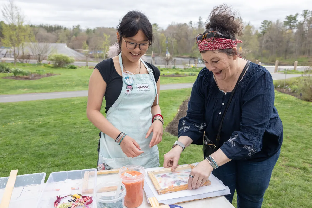 A student looks on as a community member makes paper