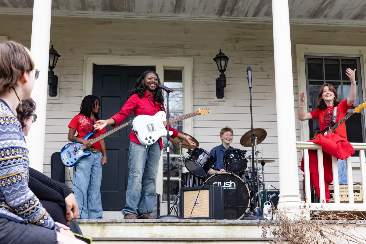 Students play instruments on a porch during Porchfest