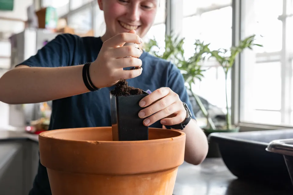 A student adds a handful of dirt to a pot in Lyman