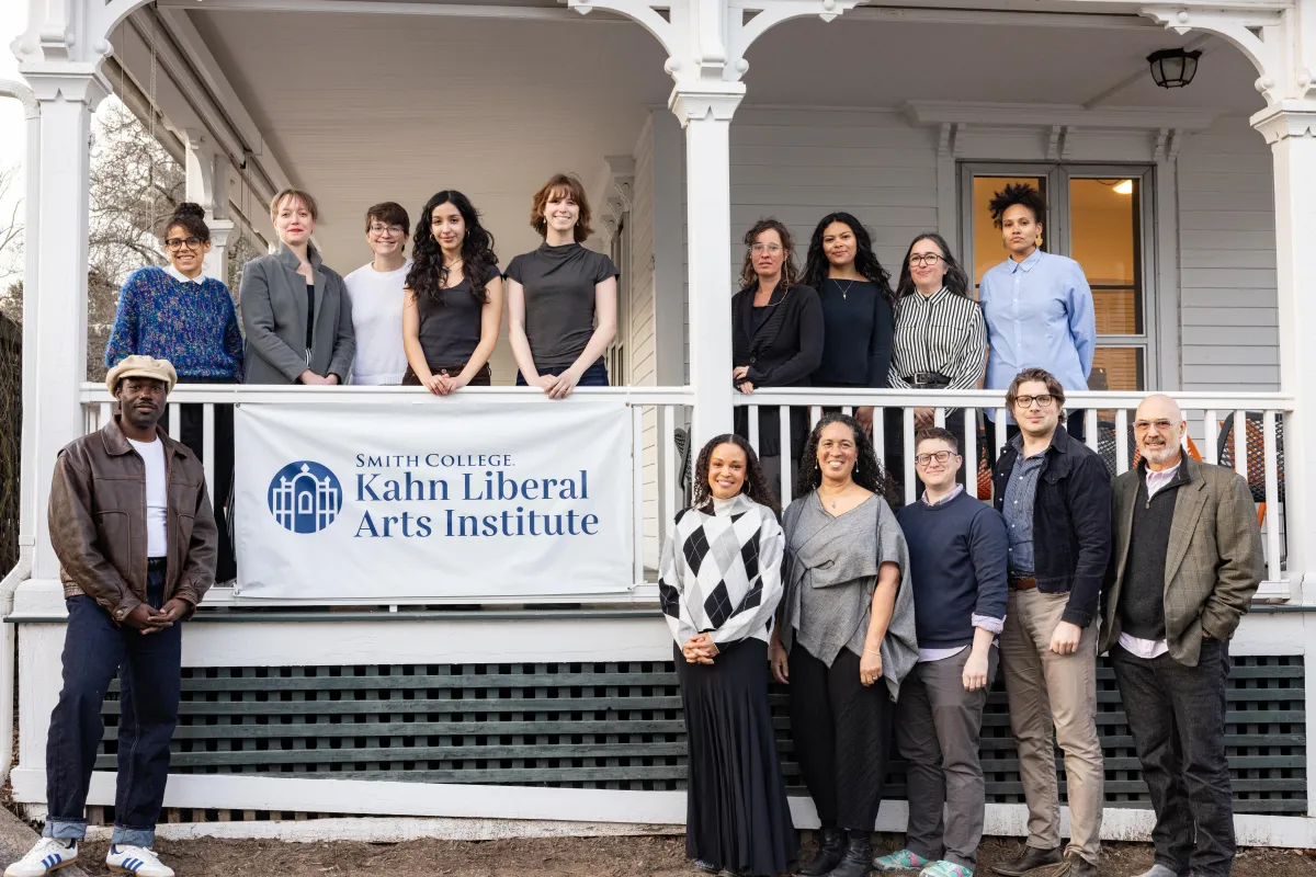 Group photo of the Hauntings fellows posed on and in front of a white porch with a Smith College Kahn Liberal Arts Institute banner.