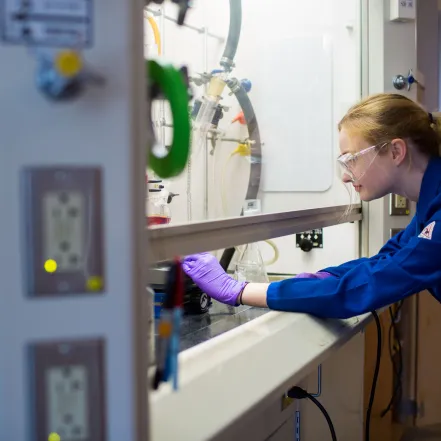 A student working in a lab, wearing safety goggles.