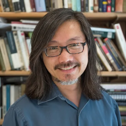 Floyd Cheung in front of a bookshelf.