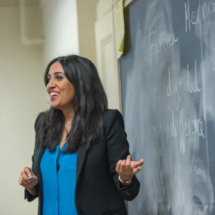 A professor pointing to a chalkboard.