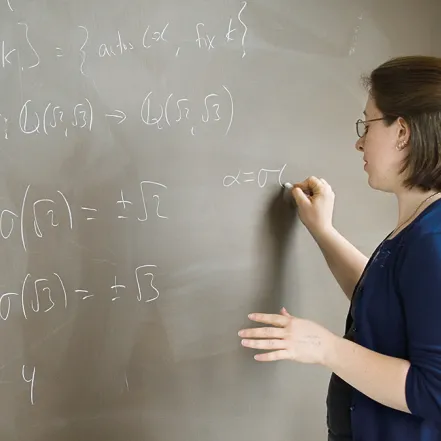 Student working on a math equation at a blackboard